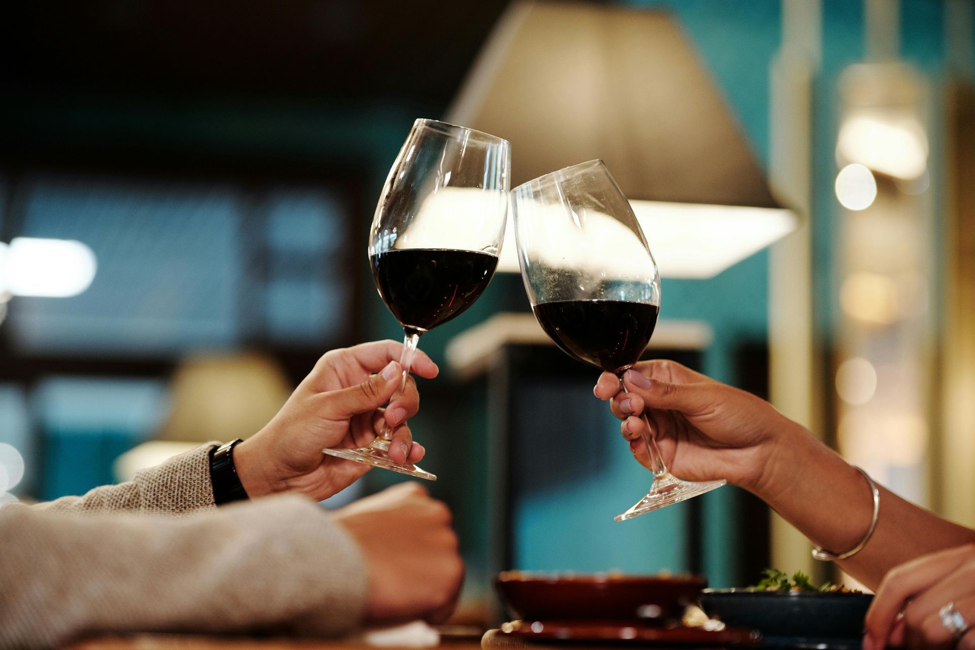 Two people are toasting with wine glasses in a restaurant.