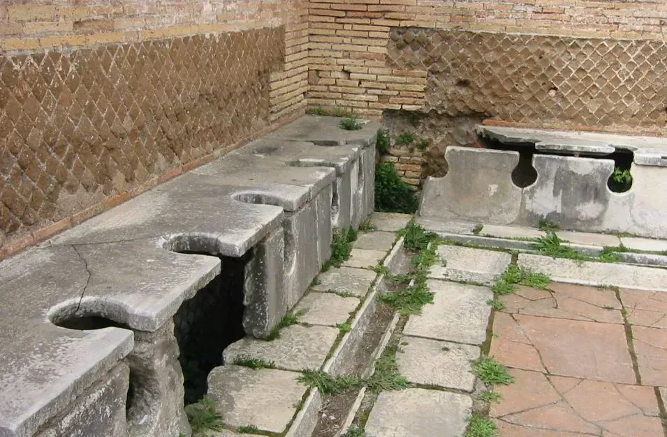 Stone outdoor washbasins along a brick wall in a courtyard with tiled flooring.