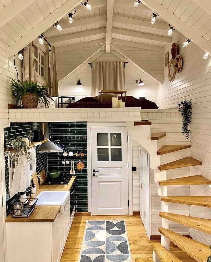 Cozy loft-style room with white walls, spiral stairs, skylight ceiling, and a small kitchen below