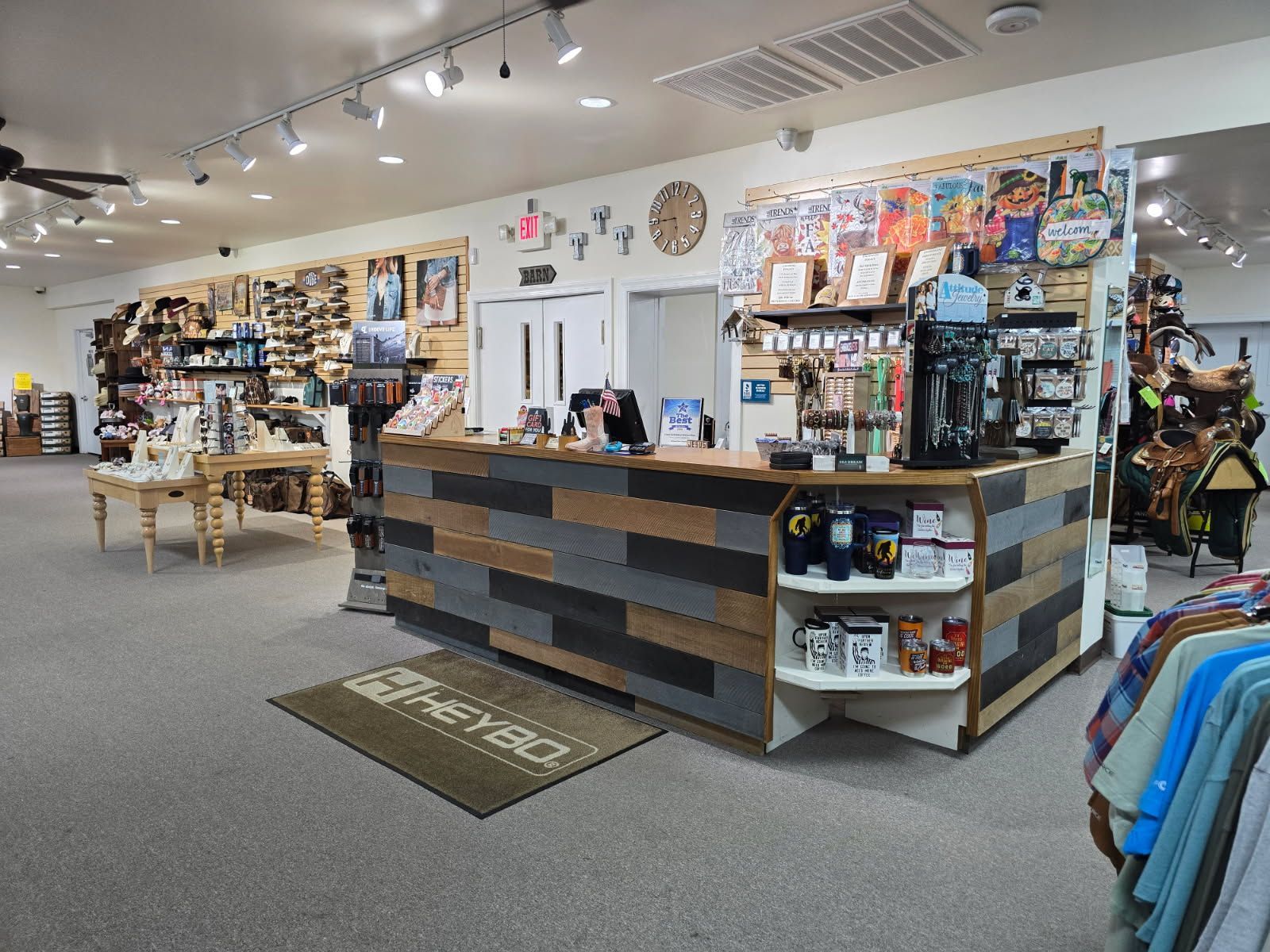 A retail store interior with a wood-paneled counter, products on display, and a Heybo welcome mat.