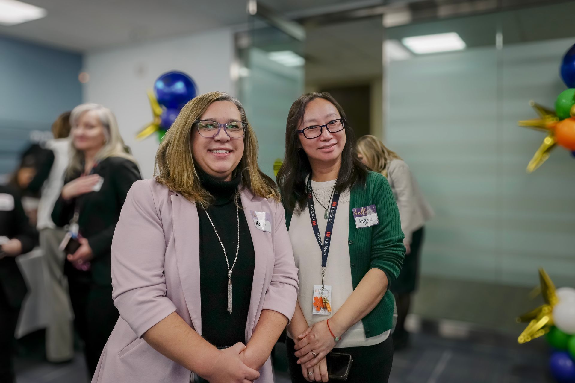 Two smiling people with lanyards standing together at an indoor event.