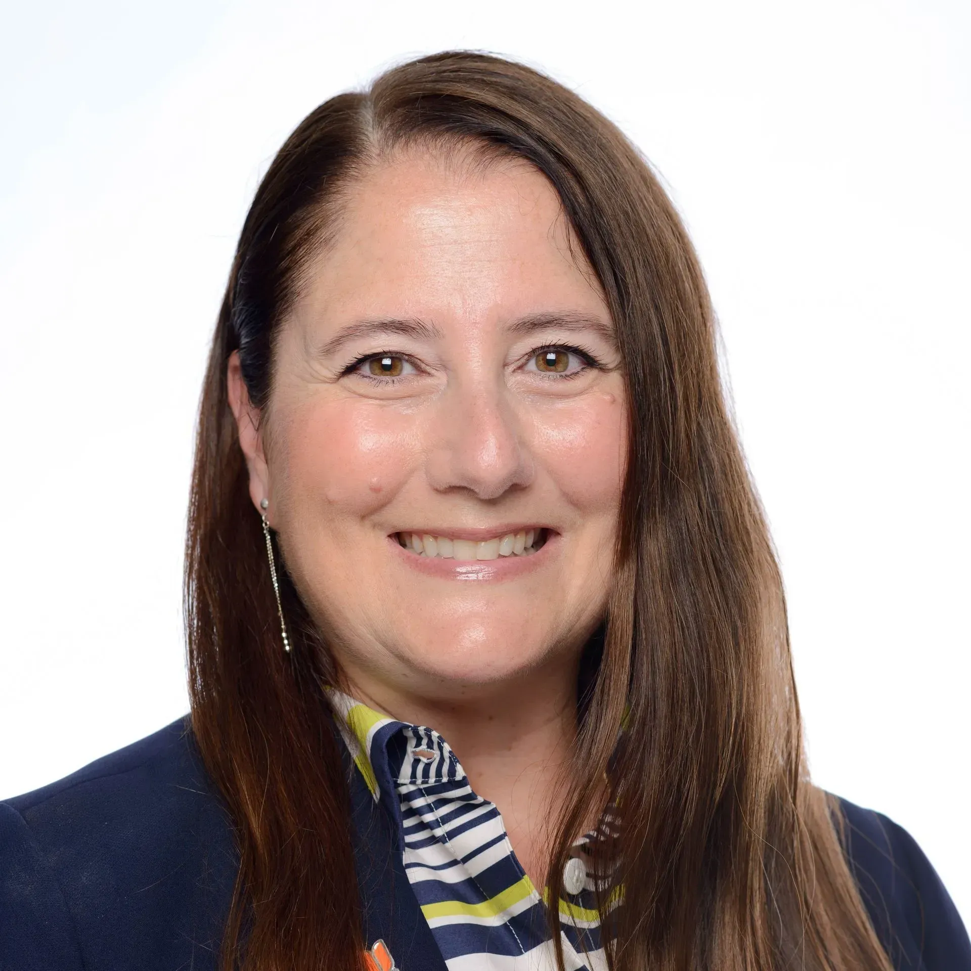 Portrait of a smiling woman with long brown hair in a dark blazer and patterned scarf on a white background