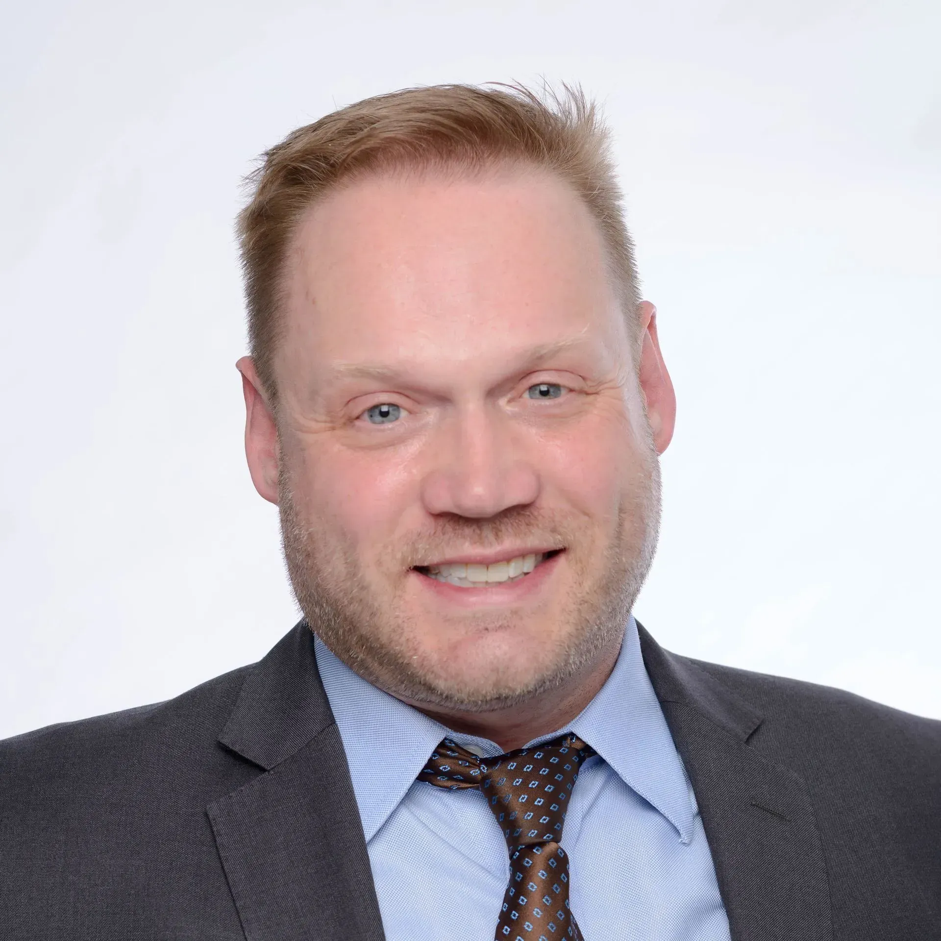 Smiling man in a suit and tie against a light background