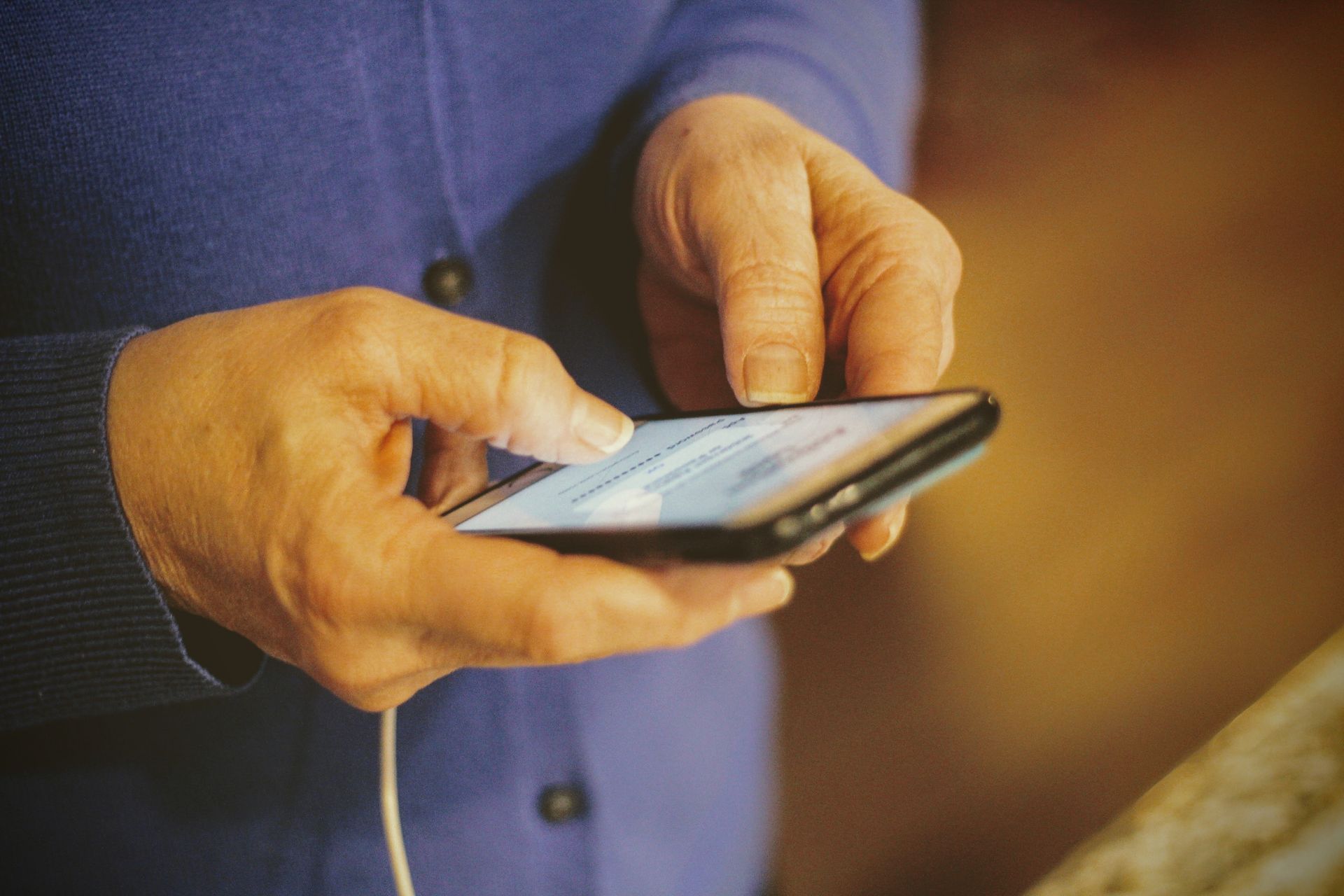 Hands using a smartphone with a messaging screen on a blue shirt background
