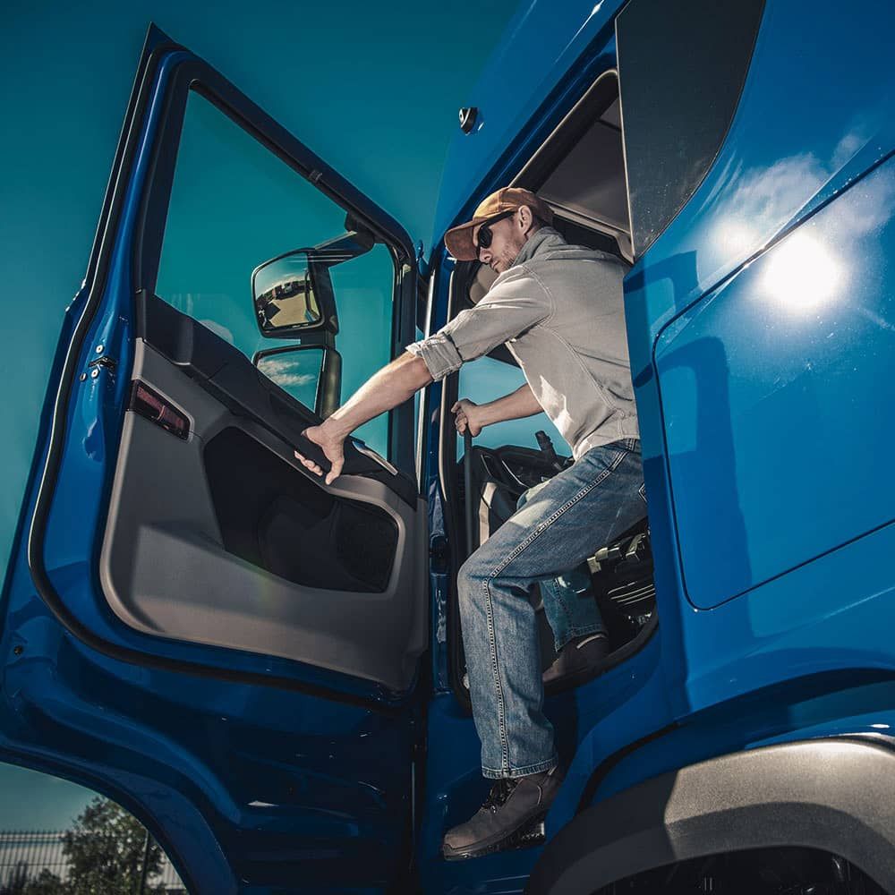 A man is getting out of a blue truck