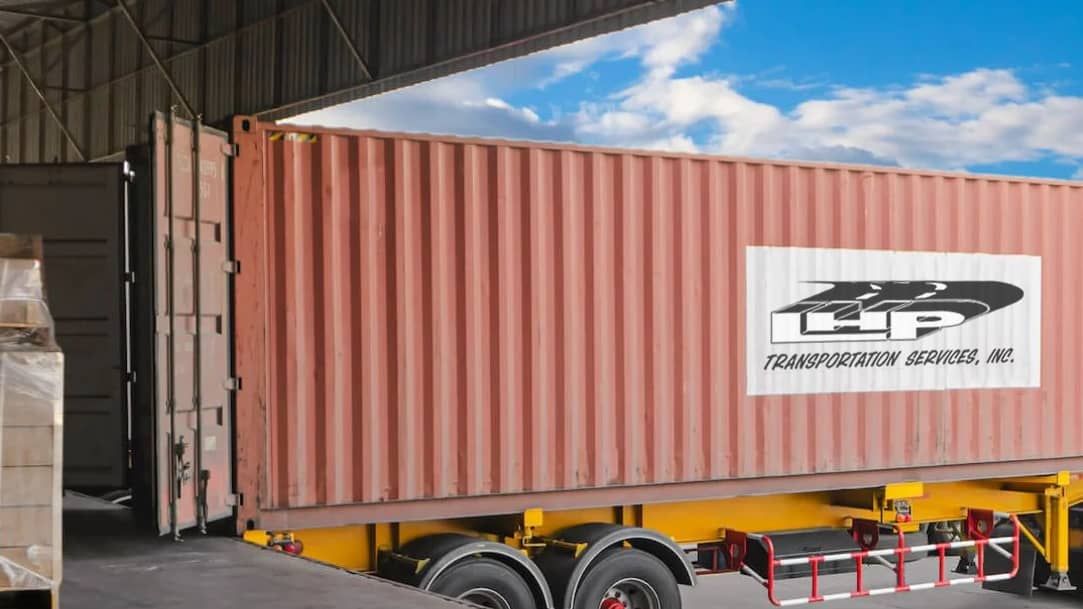 A shipping container is being loaded into a truck in a warehouse.