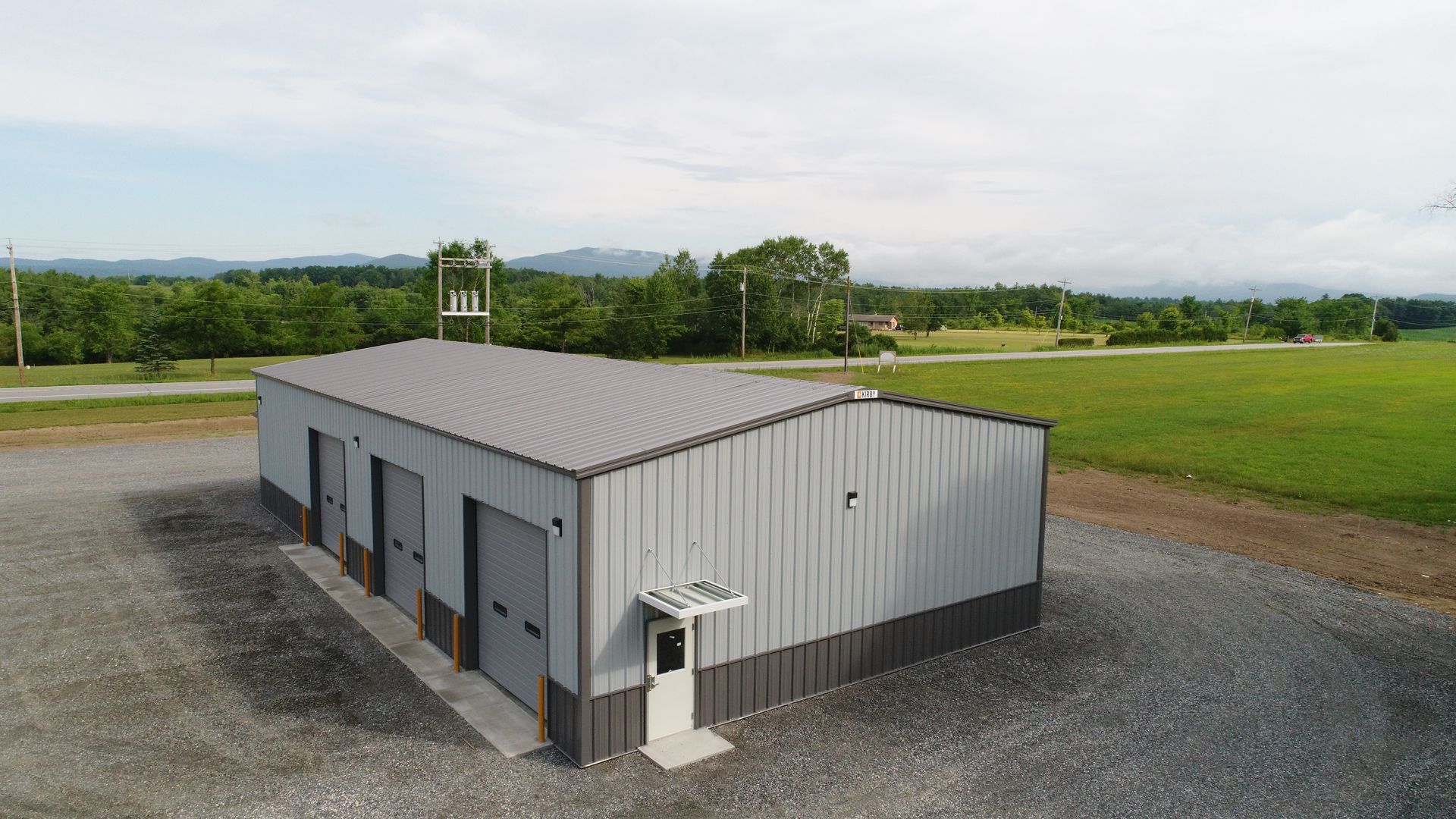 An aerial view of a large metal building in the middle of a field.