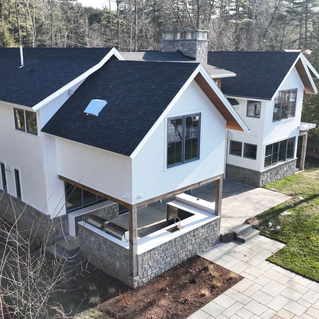 An aerial view of a white house with a black roof