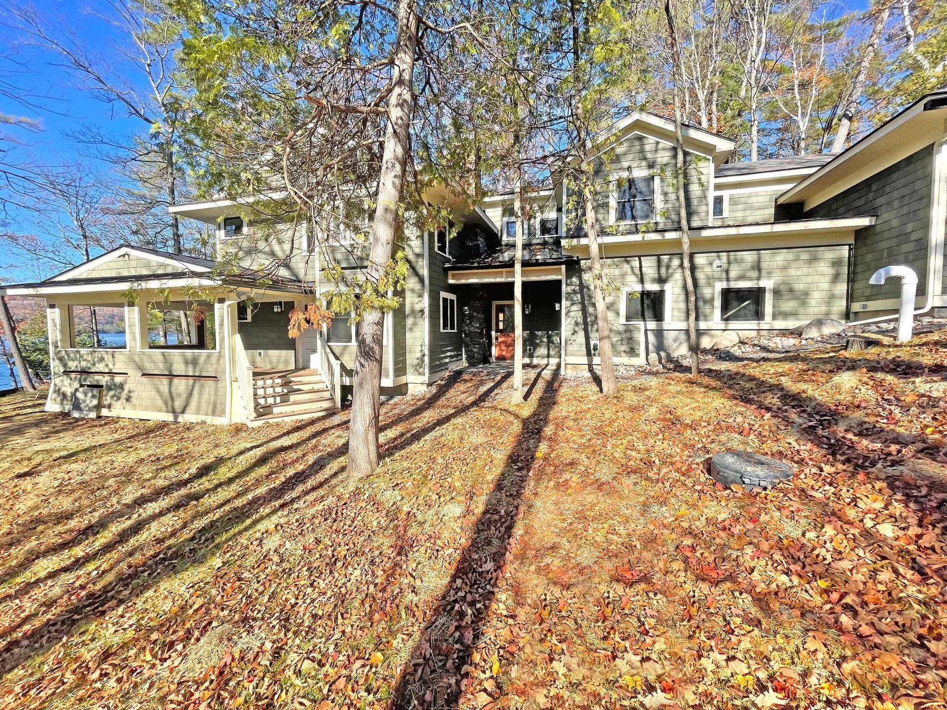 A large house is sitting on top of a hill surrounded by trees and leaves.
