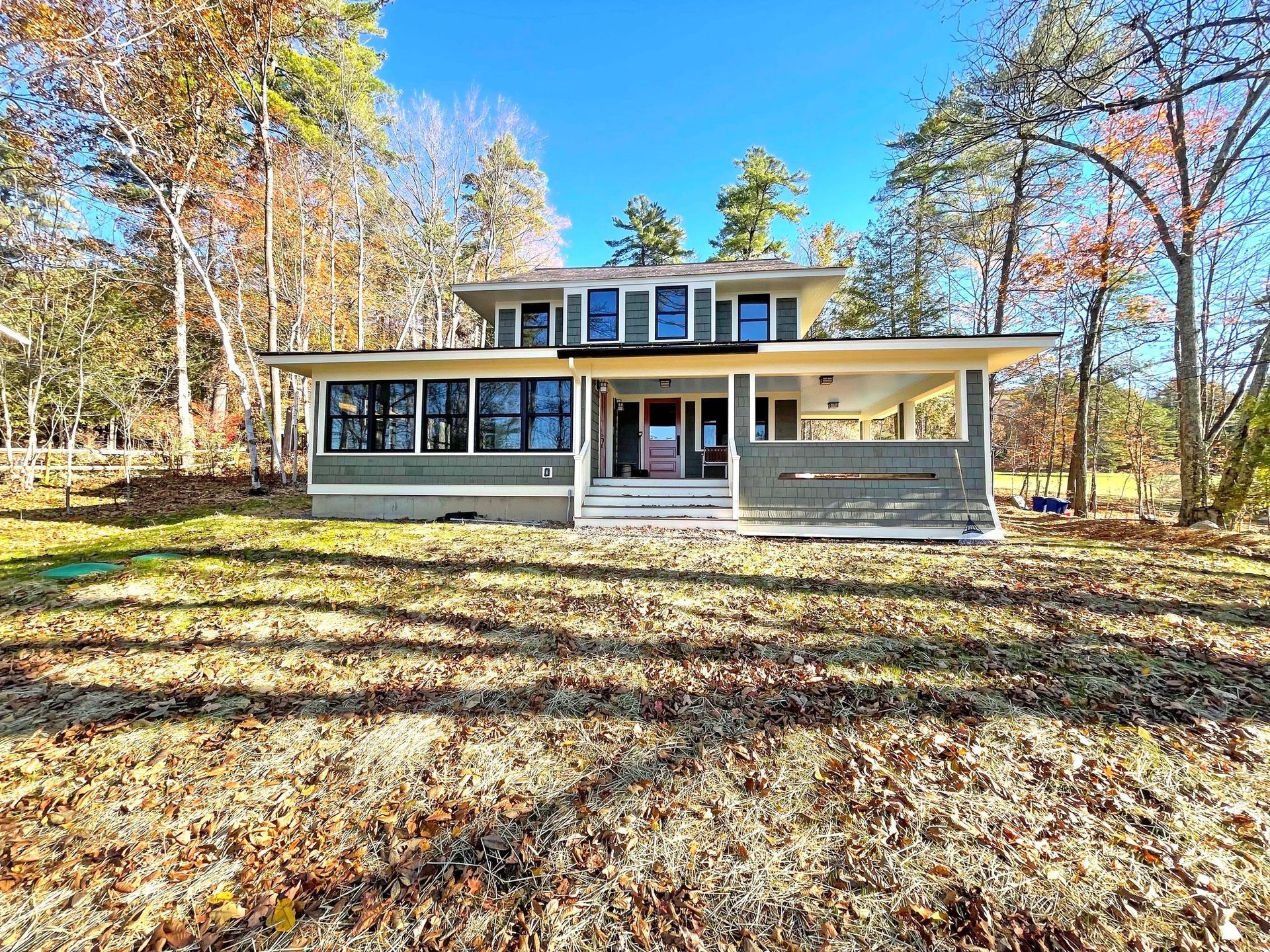 A large house is sitting on top of a lush green field surrounded by trees.