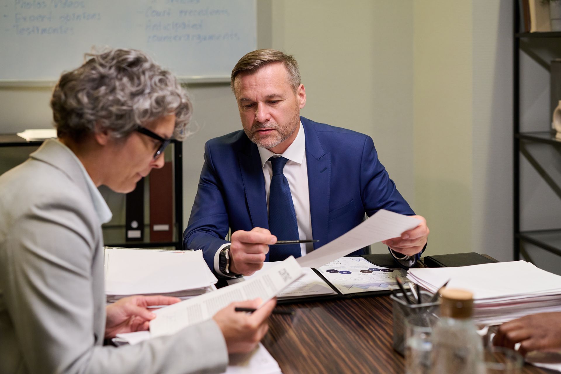 Two people in a business meeting reviewing documents at a table.