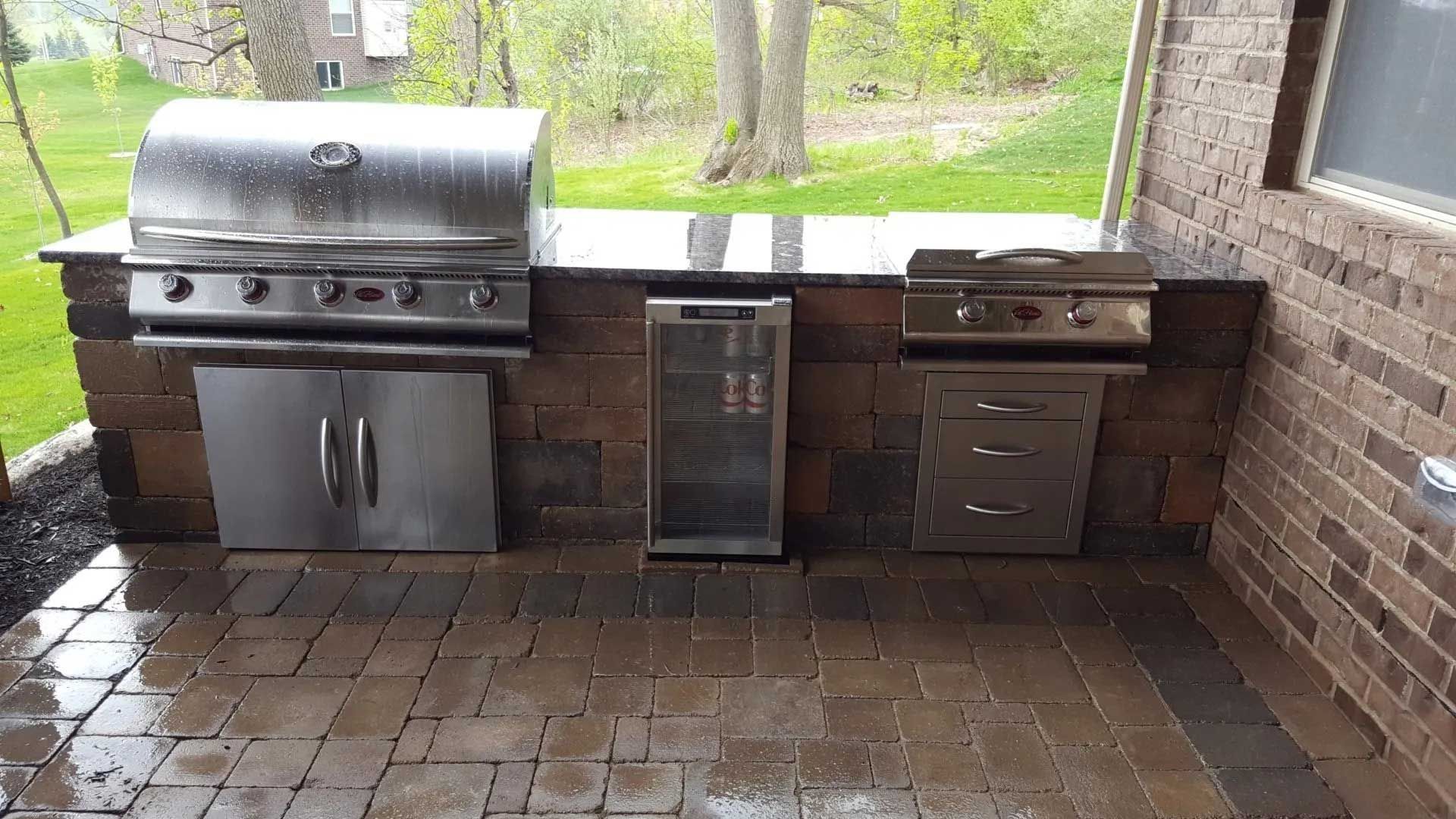 There is a grill and a refrigerator in the backyard.