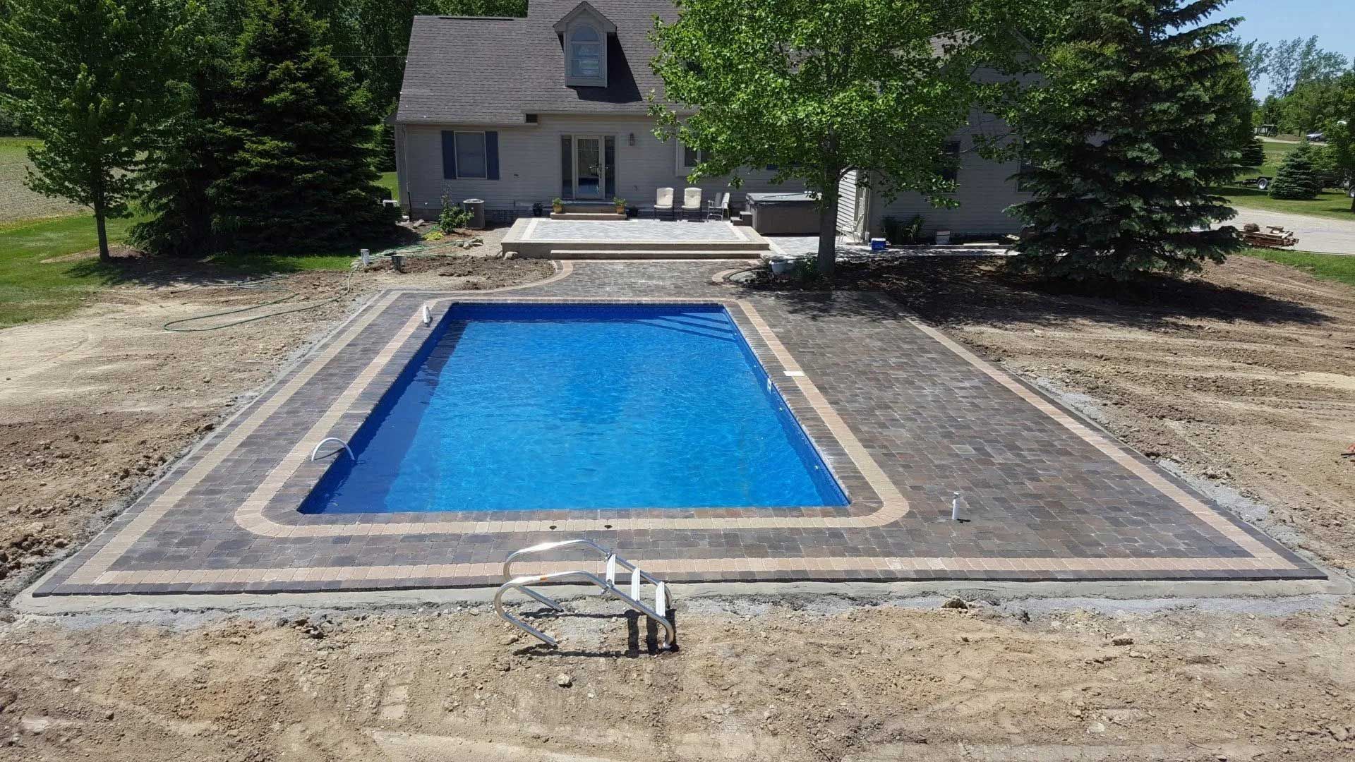 A large swimming pool is in the backyard of a house.