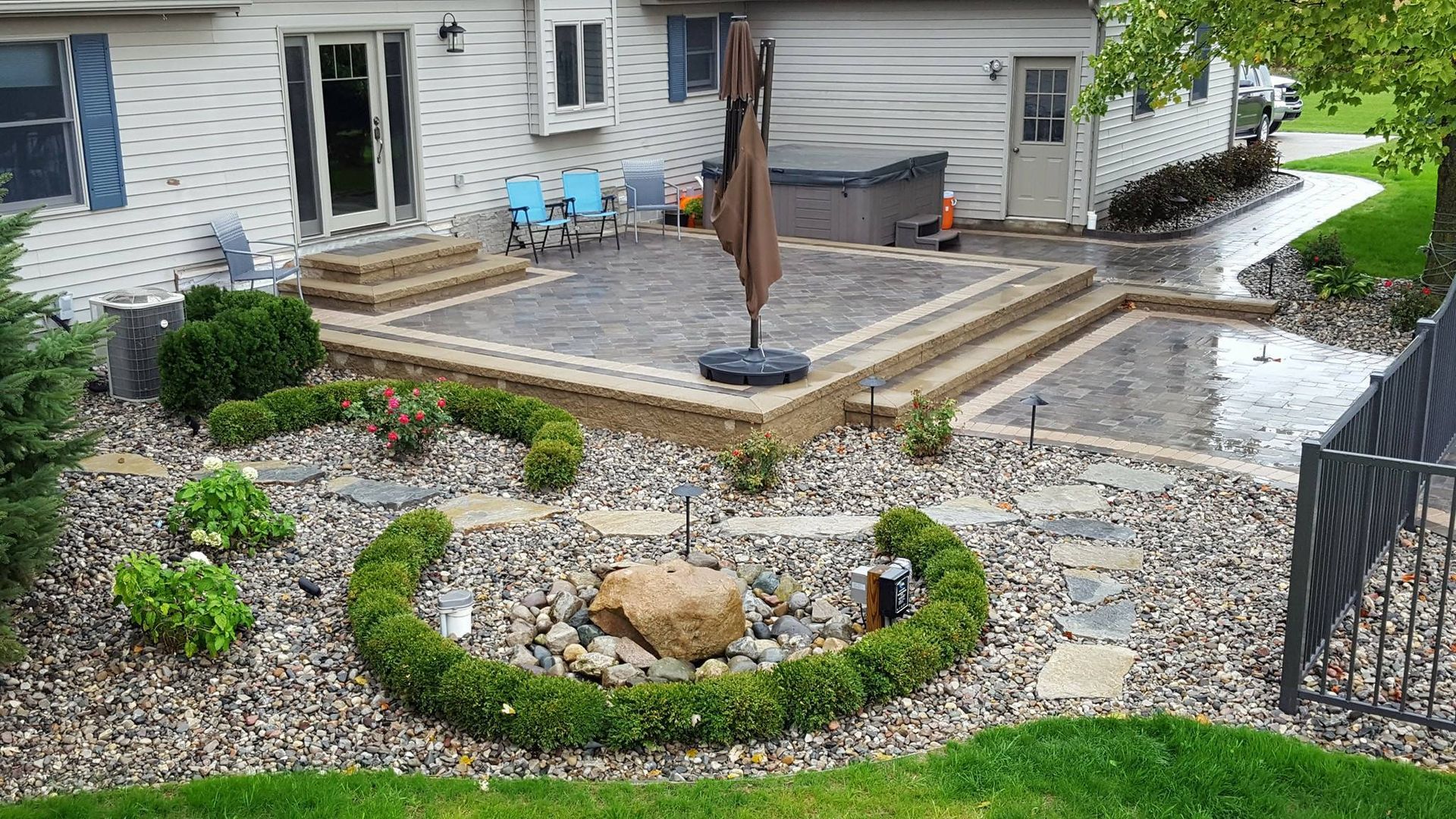 A large patio with a umbrella in the middle of it in front of a house.
