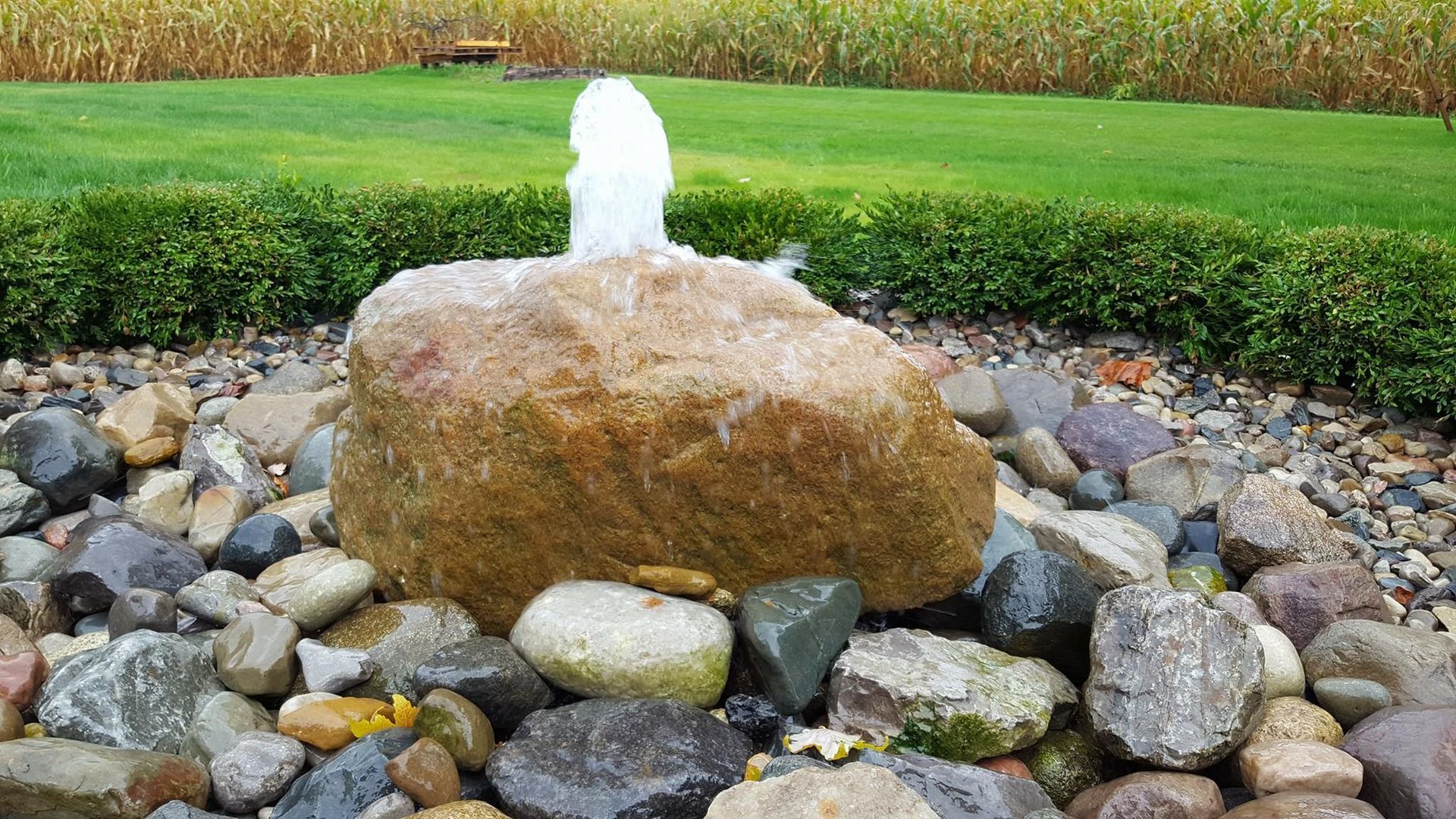 There is a fountain in the middle of a rocky area.