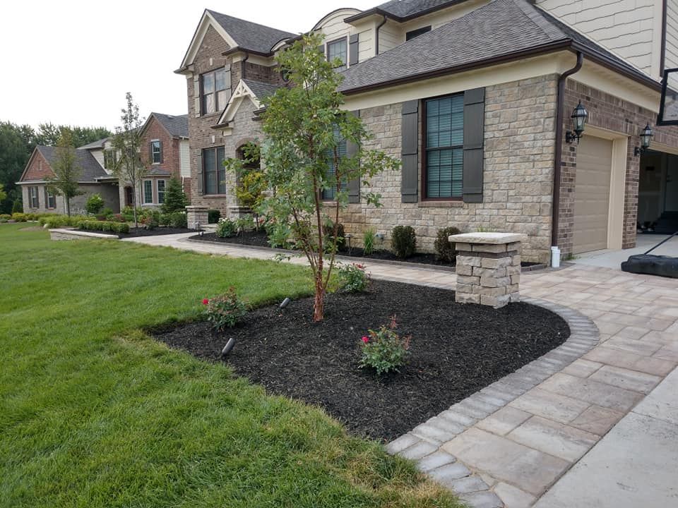 A large brick house with a lush green lawn and a walkway leading to it.