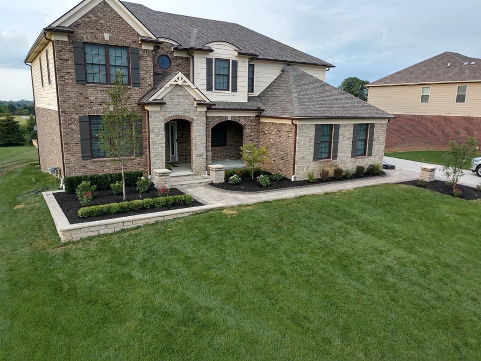 An aerial view of a large brick house with a lush green lawn.