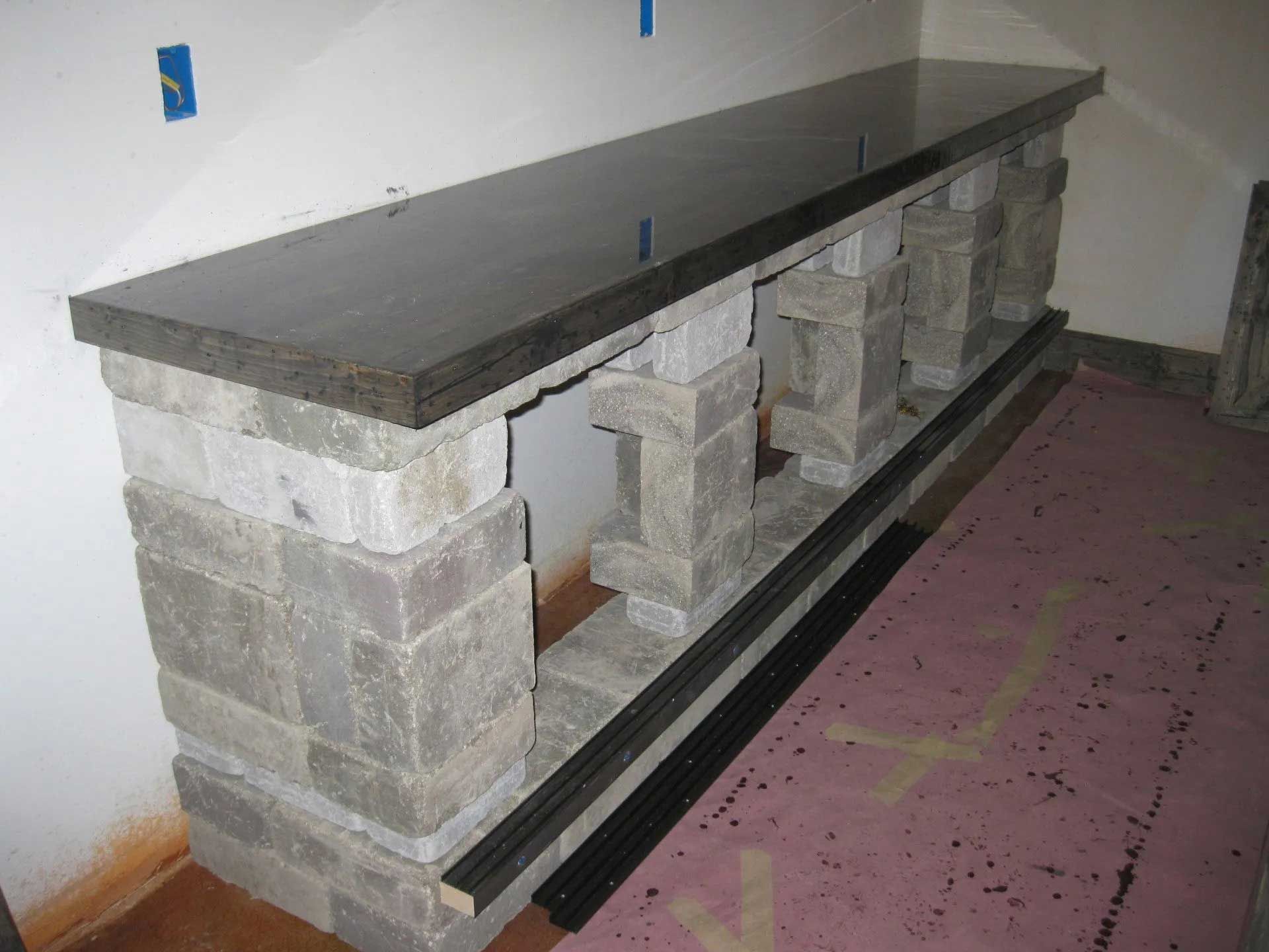 A long stone shelf is sitting on a pink rug in a room.
