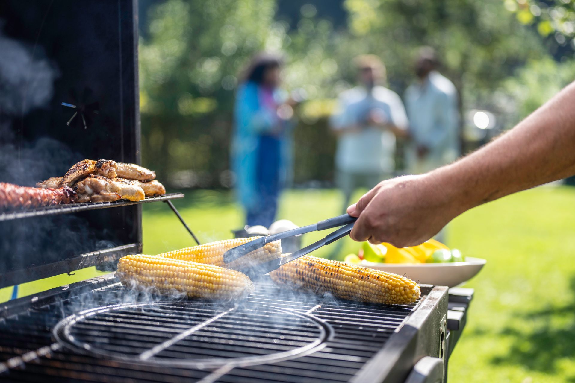 A person is grilling corn on the cob on a grill.