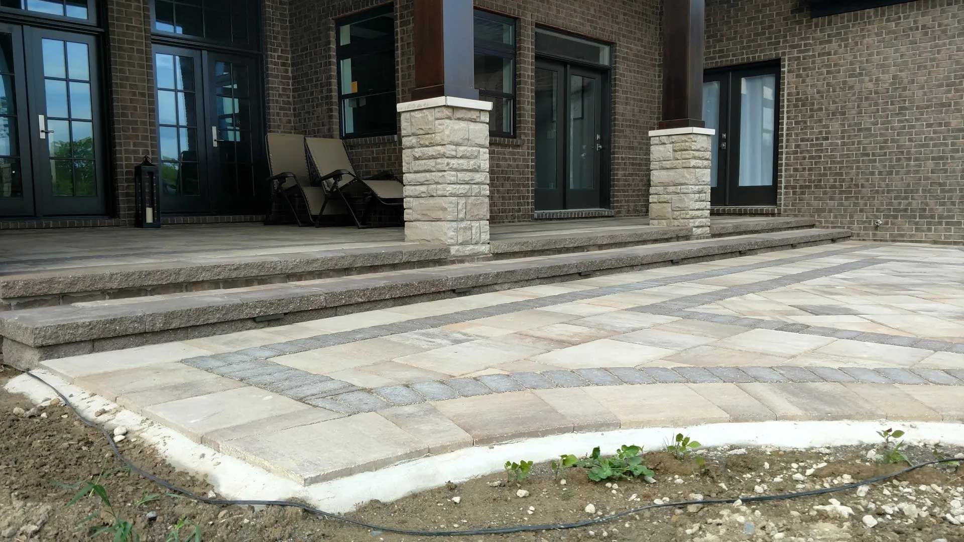 A brick house with a patio and stairs in front of it.