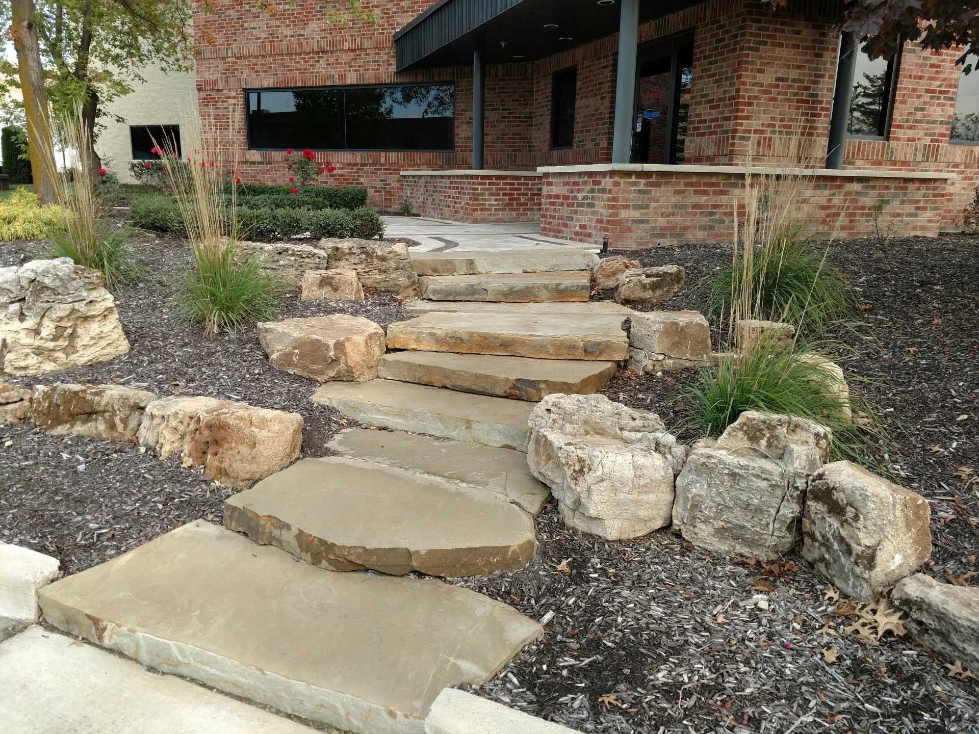 A stone walkway leading to a brick building surrounded by rocks.