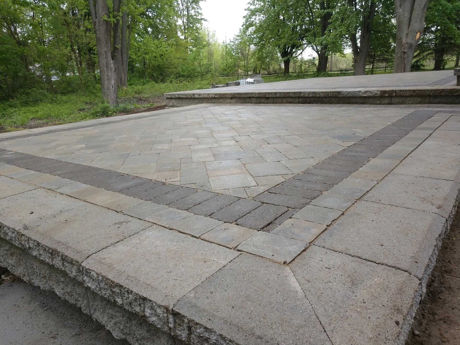 A brick walkway in a park with trees in the background