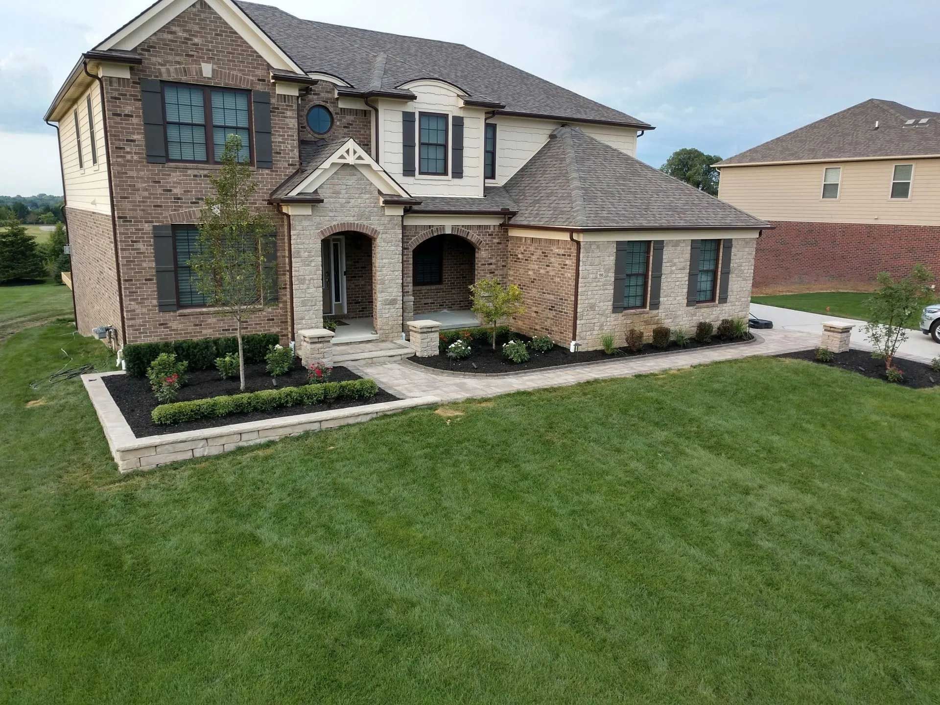 An aerial view of a large brick house with a large lawn in front of it.
