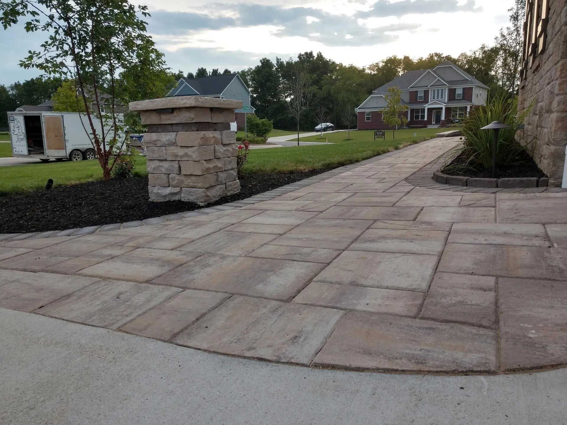 A brick walkway leading to a large house