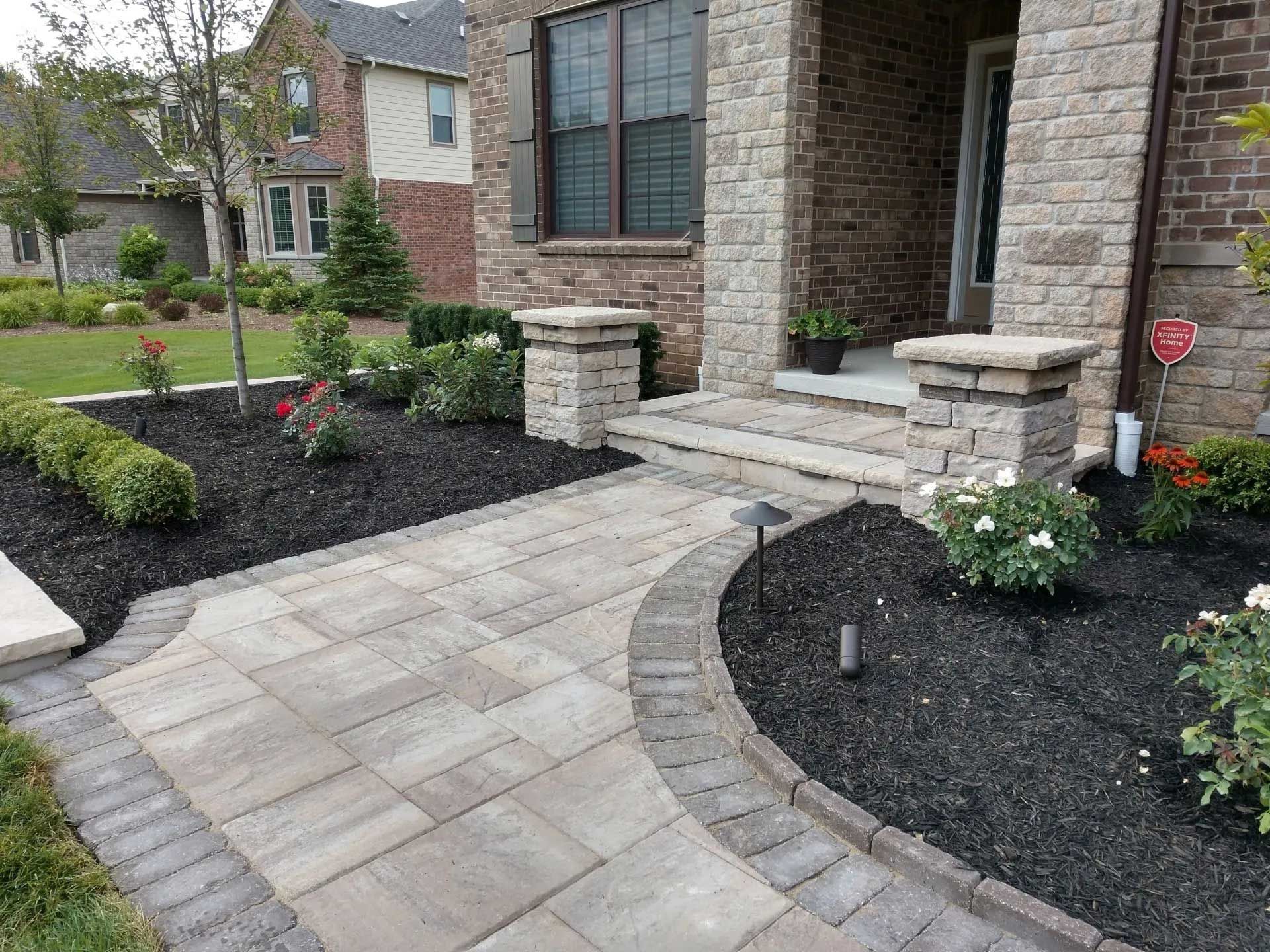 A stone walkway leading to the front door of a brick house.