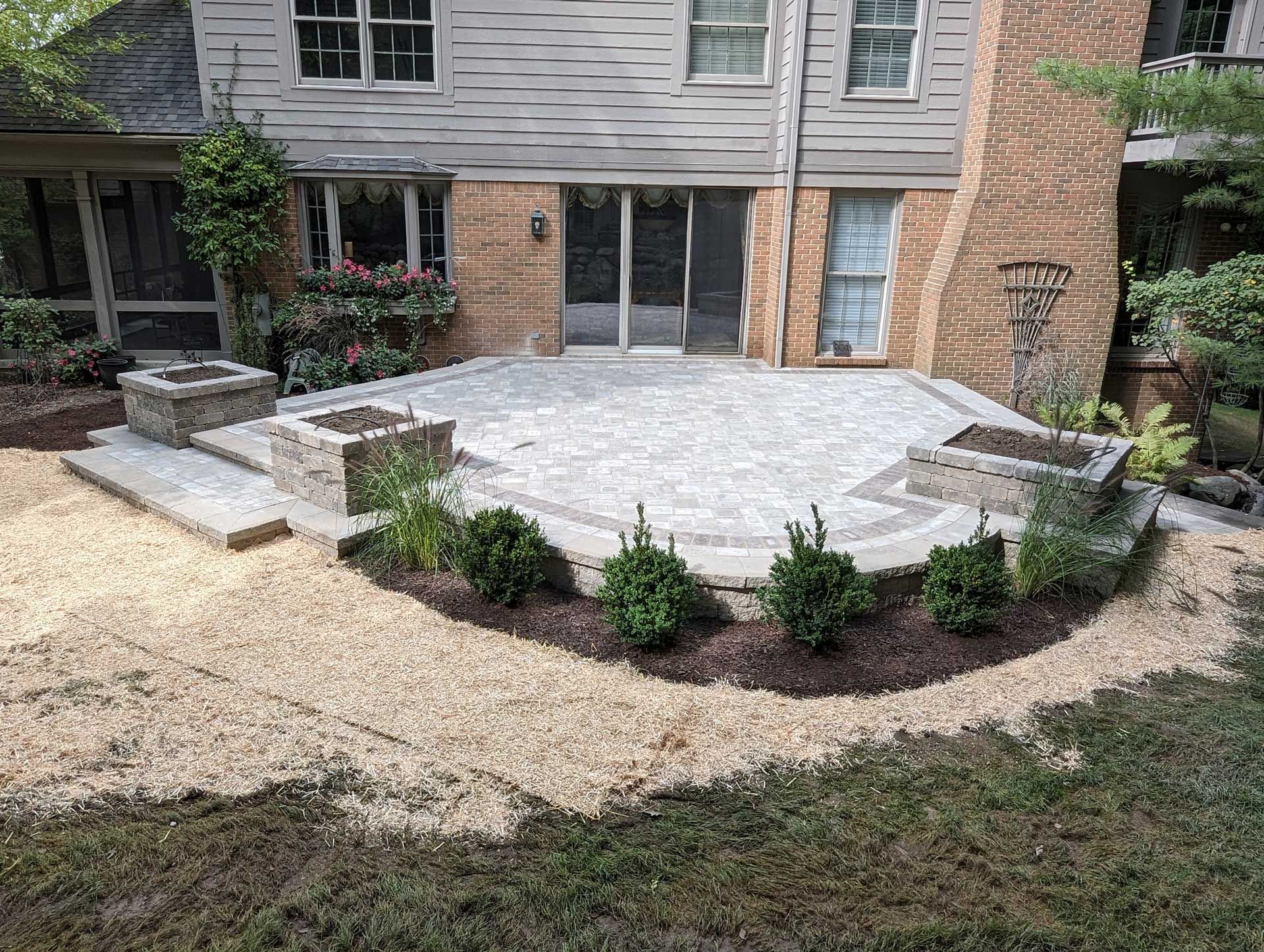 A backyard with a patio and a fire pit in front of a house.