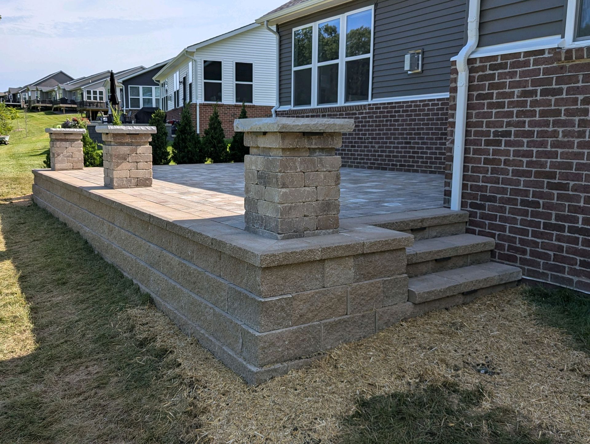A brick wall with steps leading to a patio in front of a brick house.