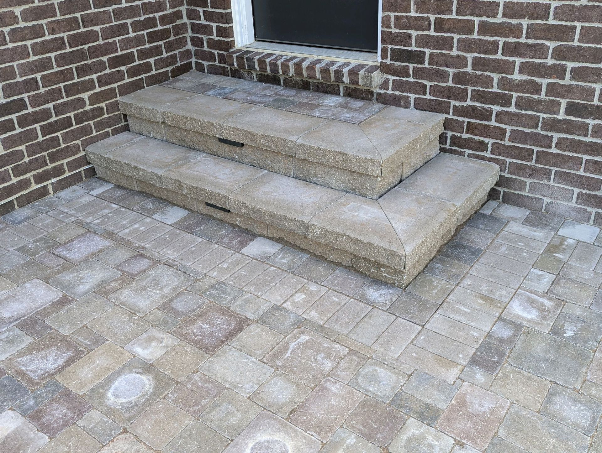 A set of steps sitting on top of a brick patio in front of a brick building.