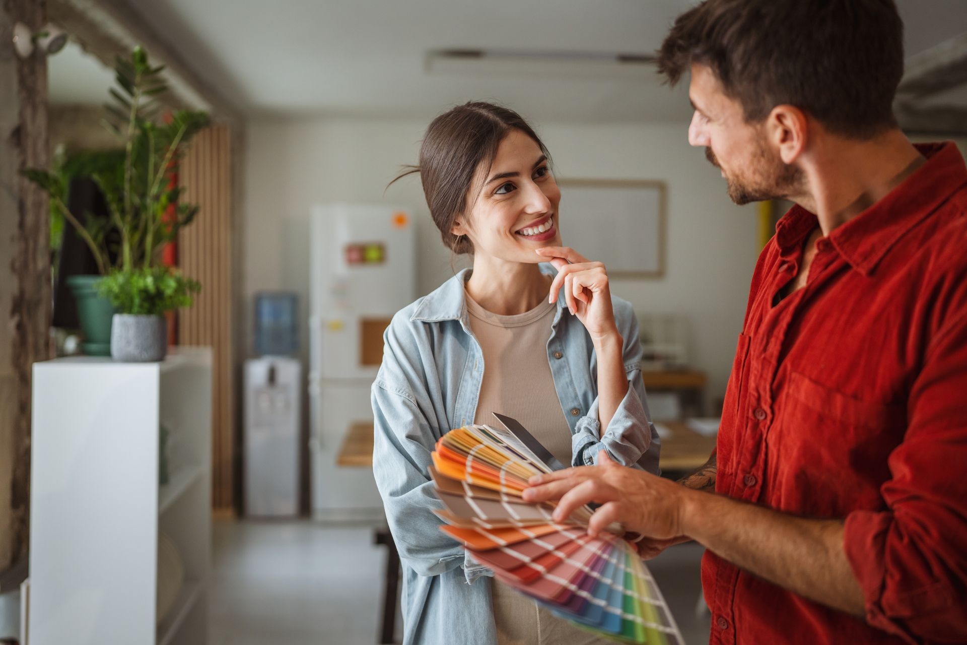 Two people discussing color swatches in a home interior setting. Two people discussing color swatches in a home interior setting.