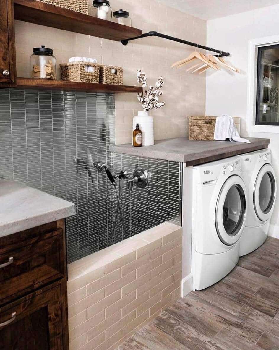 Laundry room featuring a tiled dog washing station, wooden shelves, a clothes rack, and white front-load appliances.