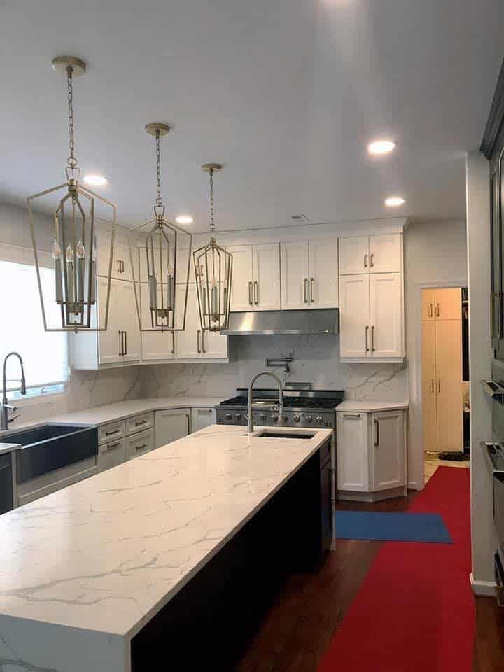 A kitchen with white cabinets, granite countertops, stainless steel appliances, and wood-look flooring.