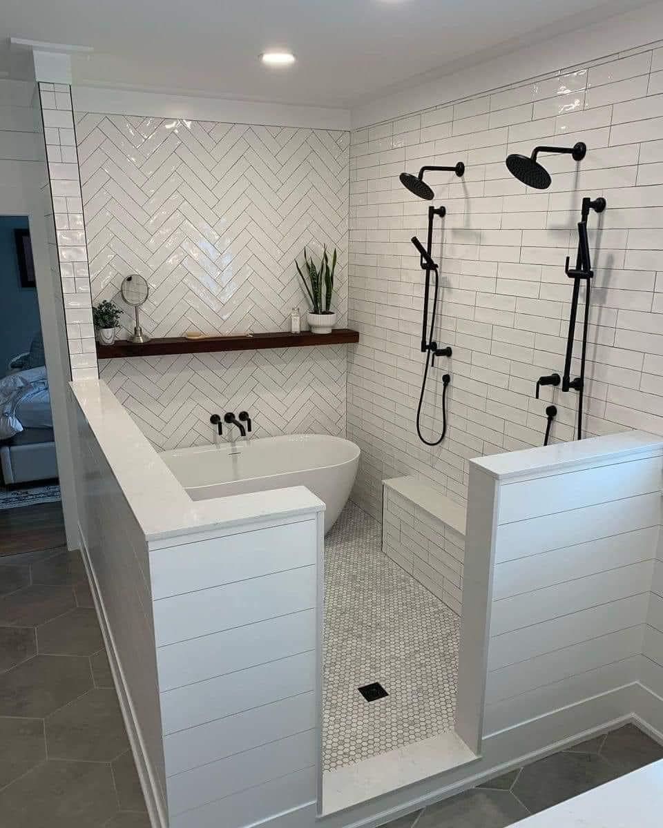 A modern bathroom featuring a white soaking tub, a double shower with black fixtures, and white herringbone tiled walls. A modern bathroom featuring a white soaking tub, a double shower with black fixtures, and white herringbone tiled walls.