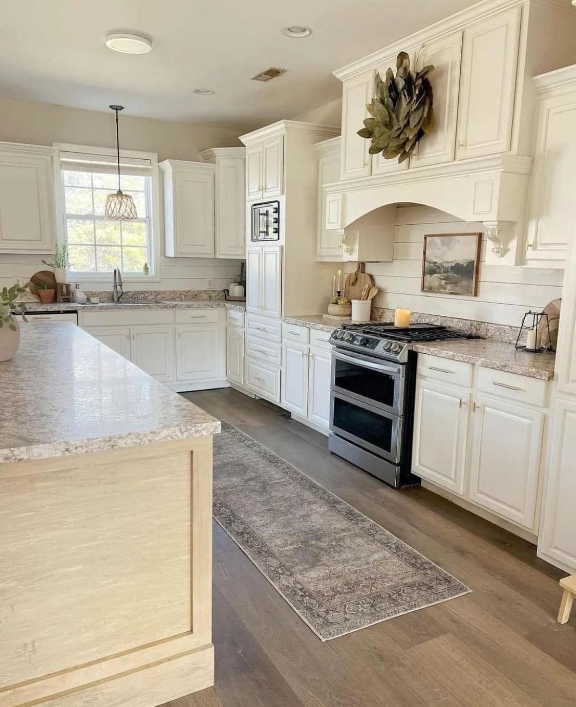 Bright white farmhouse kitchen with marble island, black stove, white cabinets, and patterned runner rug. Bright white farmhouse kitchen with marble island, black stove, white cabinets, and patterned runner rug.