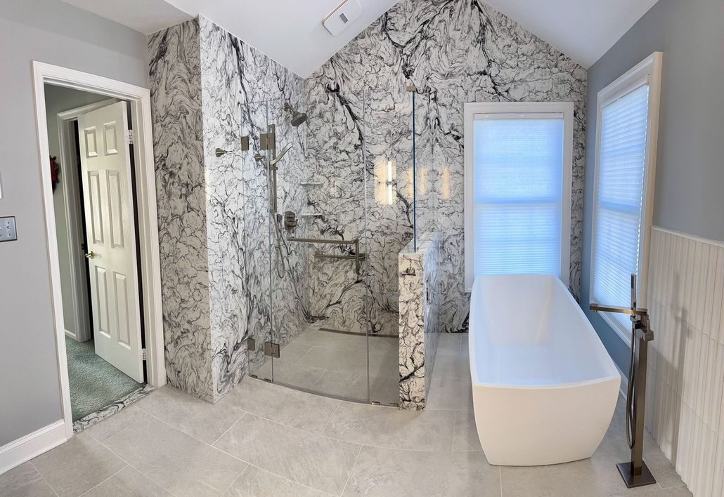 A modern bathroom featuring a freestanding tub and a glass-enclosed shower with bold, black-and-white marble-style tiling. A modern bathroom featuring a freestanding tub and a glass-enclosed shower with bold, black-and-white marble-style tiling.