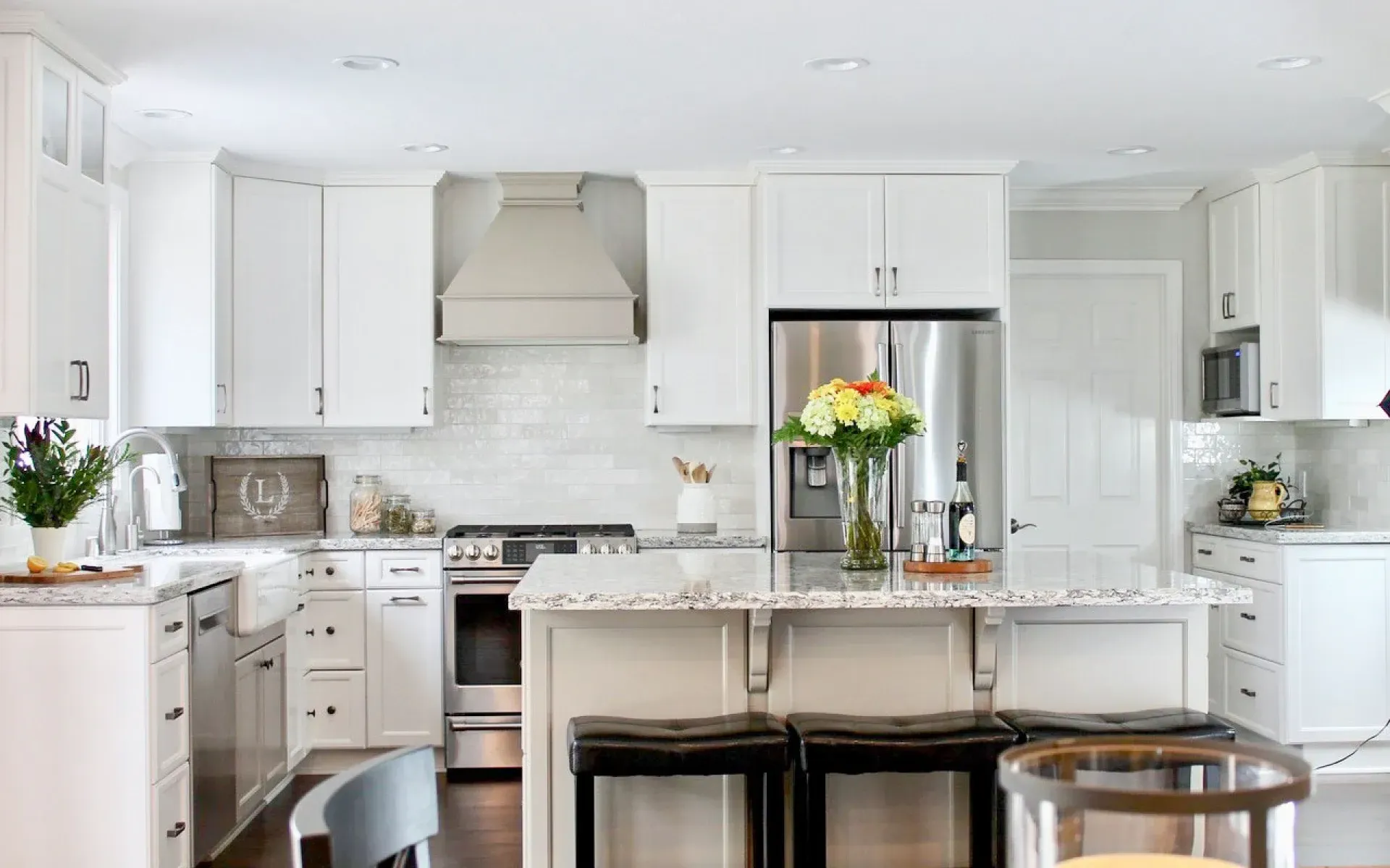 Bright, modern kitchen with white cabinets, stainless steel appliances, a center island with stools, and subway tile. Bright, modern kitchen with white cabinets, stainless steel appliances, a center island with stools, and subway tile.