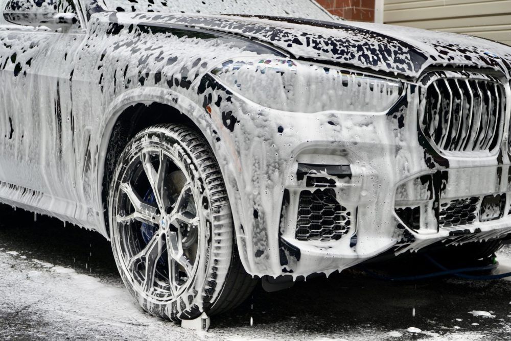 A bmw x5 is covered in foam while being washed.