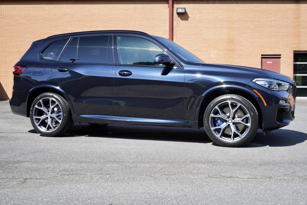 A black bmw x5 is parked in front of a brick building.