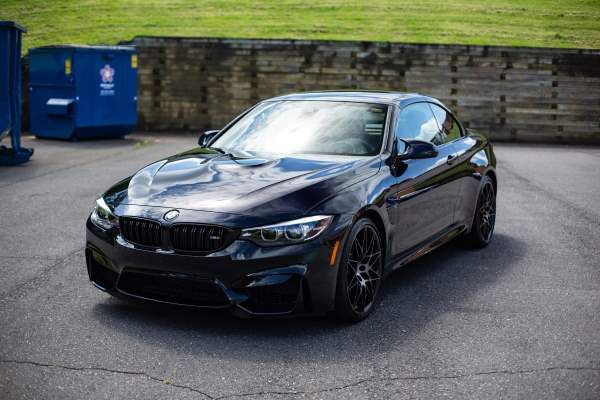 A black bmw m4 is parked in a parking lot.