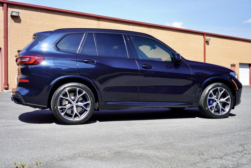 A blue bmw x5 is parked in front of a brick building.