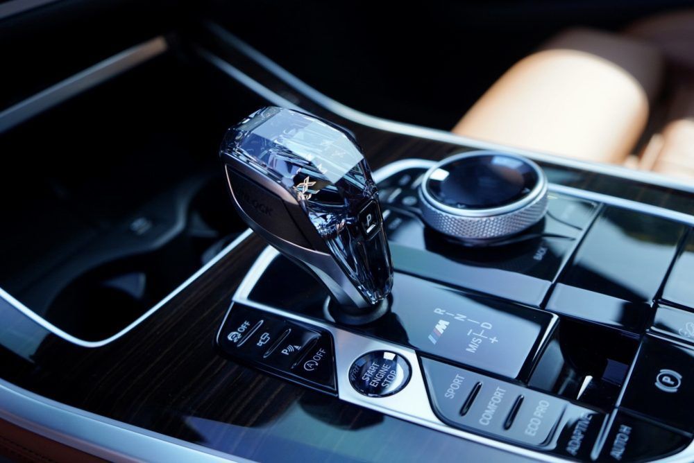 A close up of a car dashboard with a shifter and buttons