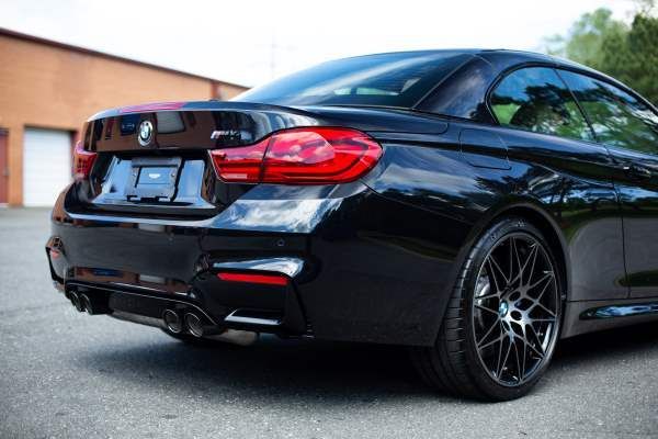 A black bmw convertible is parked in a parking lot.