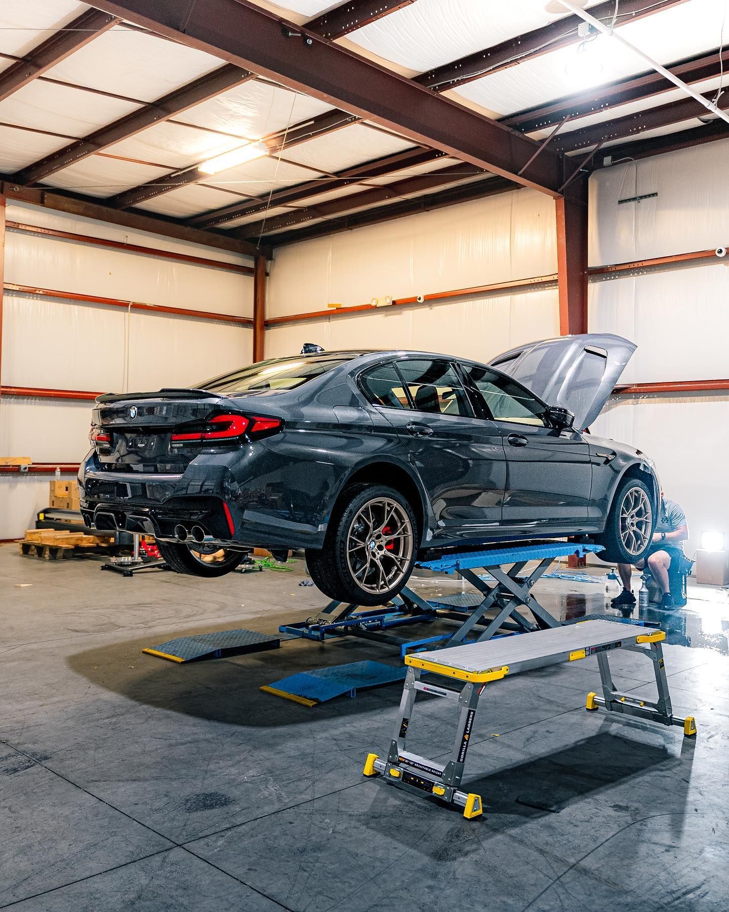 A car is sitting on a lift in a garage.