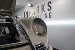 A car is covered in plastic wrap in a garage.