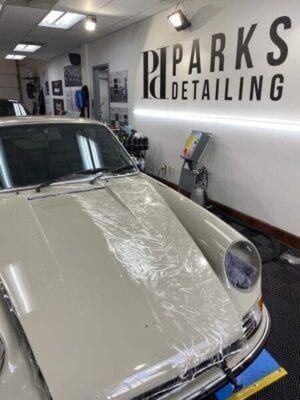 A white car is wrapped in plastic in a garage.