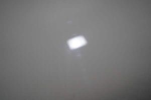 A white light is shining through a hole in the wall.