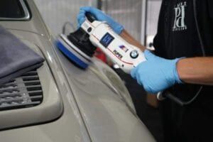 A person is polishing a car with a machine.